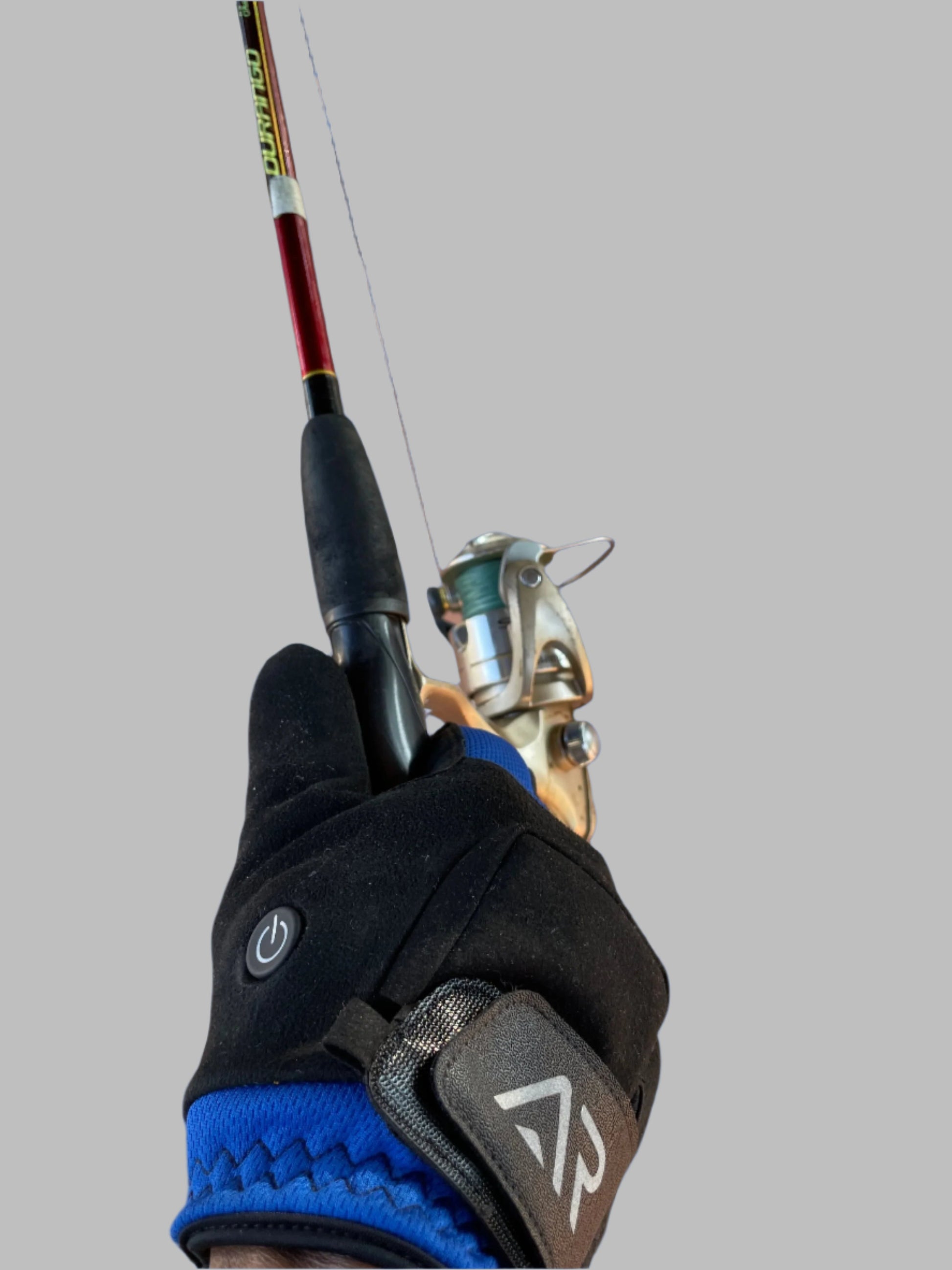An arcticreaction Black & Blue GEN2 Heated Sports Glove is holding a fishing rod against a solid blue background. The glove, with its sleek black design and blue trim, offers touchscreen compatibility and features a power symbol on the wrist area for enhanced usability. The rod is equipped with a metallic reel, primed for any weather conditions.